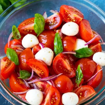 A bowl of tomato salad garnished with fresh basil.