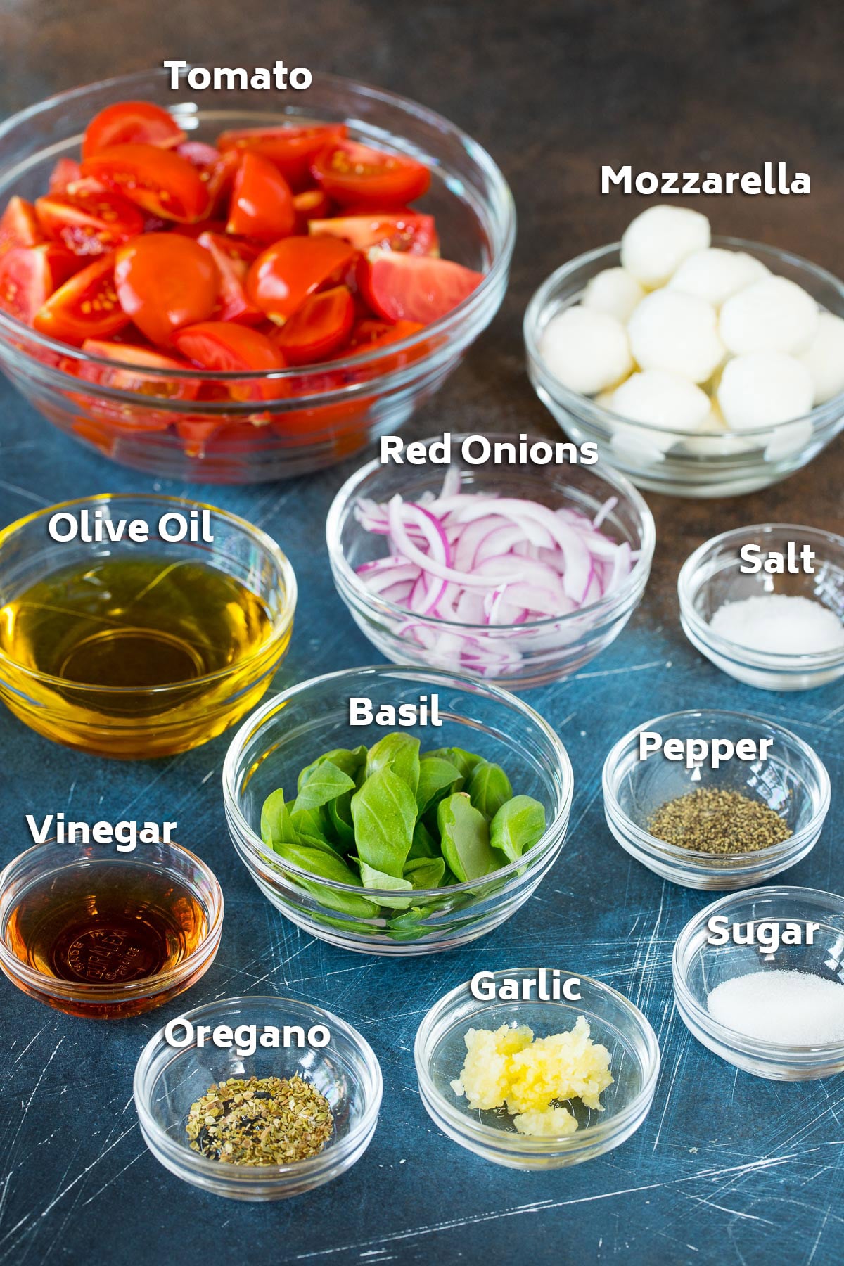 Bowls of ingredients including tomatoes, basil, cheese, onions, olive oil and seasonings.