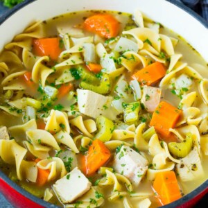 Turkey soup with egg noodles and colorful vegetables in a pot.