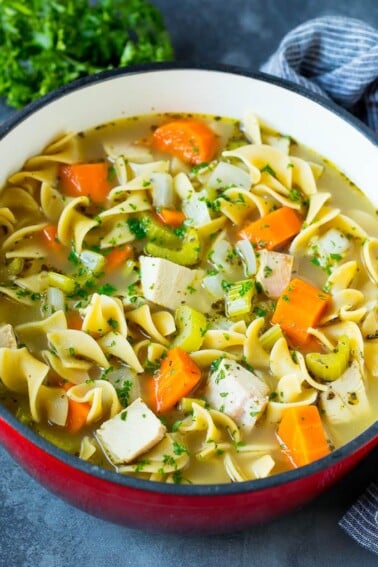 Turkey soup with egg noodles and colorful vegetables in a pot.