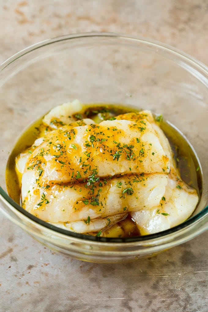 Fish fillets in a bowl of marinade.