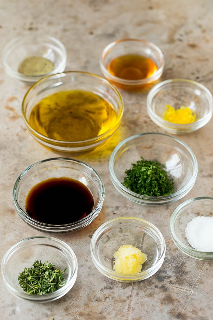 Bowls of marinade ingredients including fresh herbs, garlic, olive oil and seasonings.