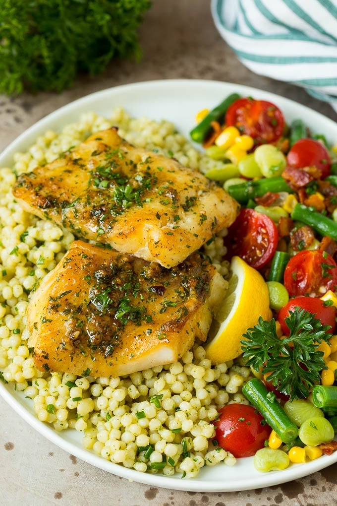 Baked cod served with couscous and mixed vegetables.