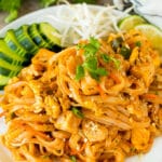 A plate of chicken pad thai served with bean sprouts and cucumber.