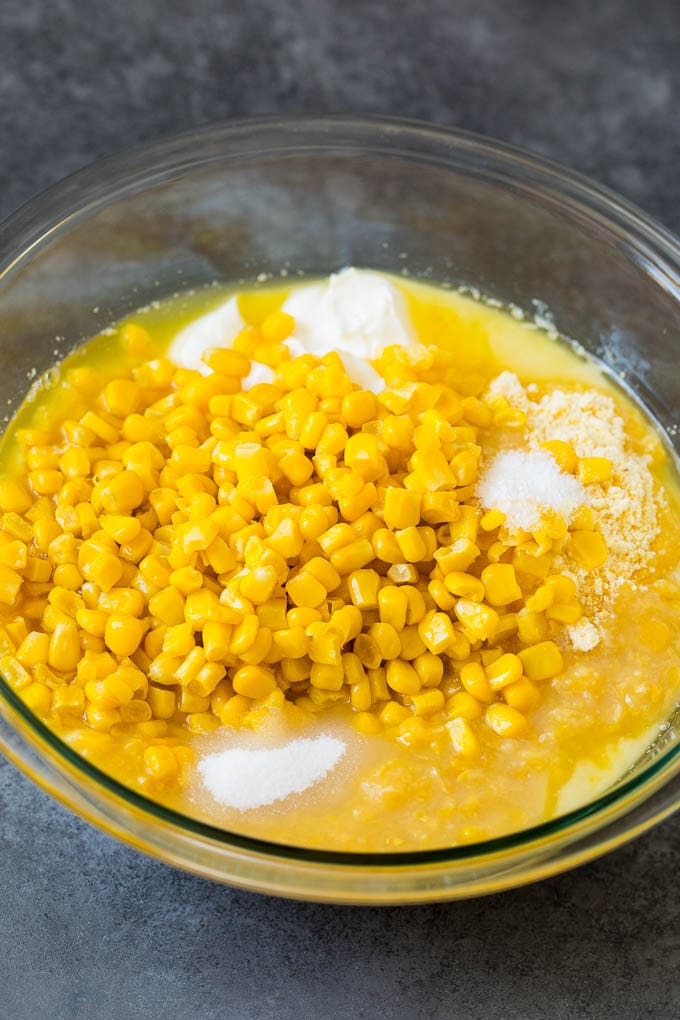 Corn muffin mix, corn kernels, sour cream and seasonings in a bowl.