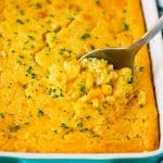 A dish of corn souffle with a serving spoon in it.