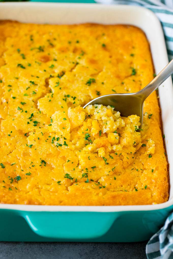 A dish of corn souffle with a serving spoon in it.