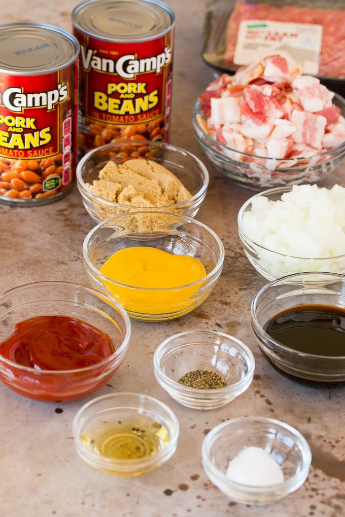Recipe ingredients including cans of beans, bacon, ground beef and bowls of seasonings.