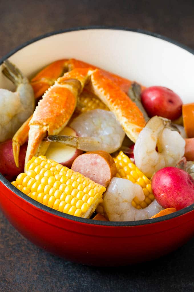 Assorted seafood, sausage and corn in a red pot.