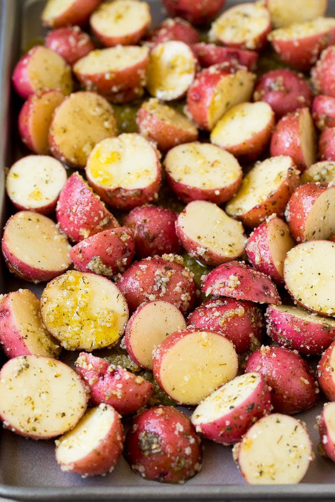Red potatoes coated in seasonings on a sheet pan.