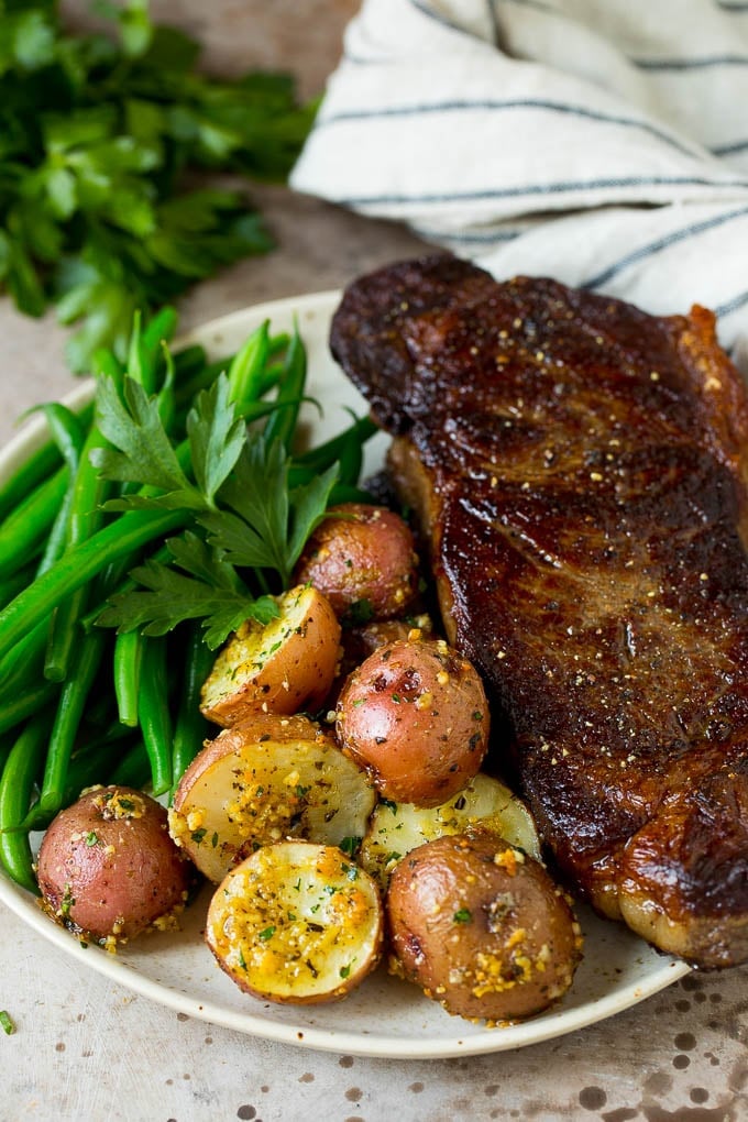 Oven roasted potatoes on a plate with steak and green beans.