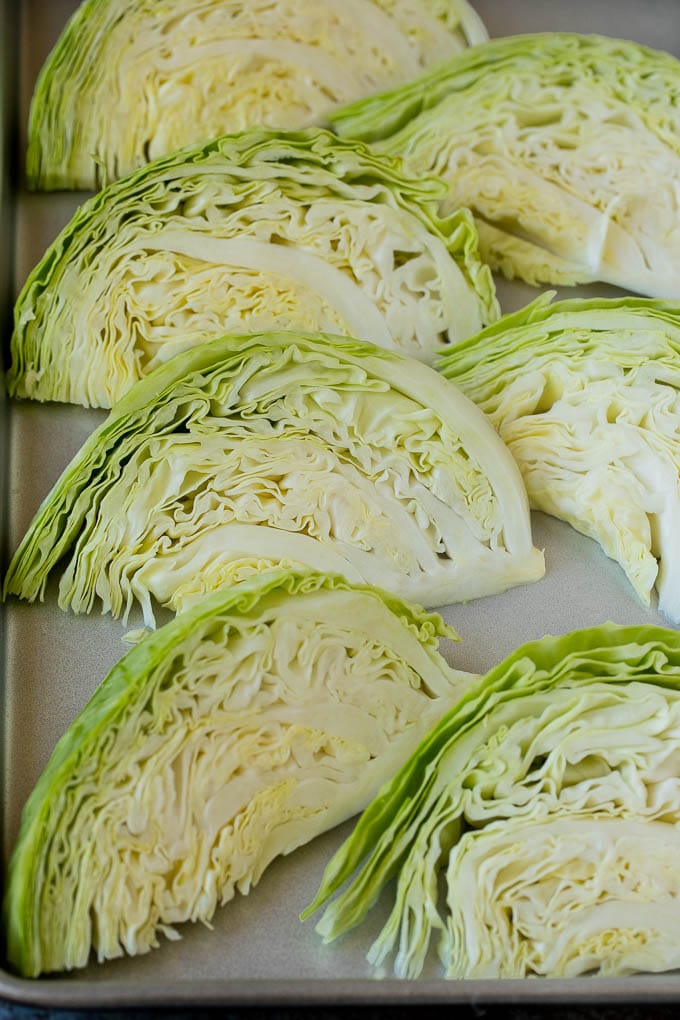 Raw cabbage wedges on a pan.
