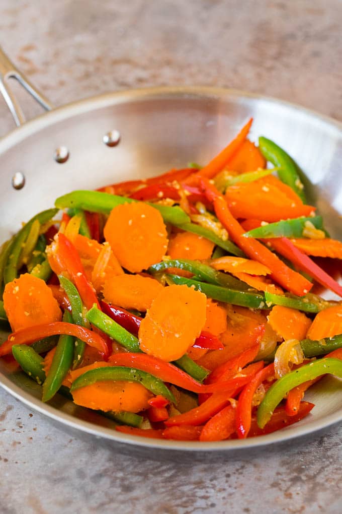 Sauteed carrots and peppers in a pan.