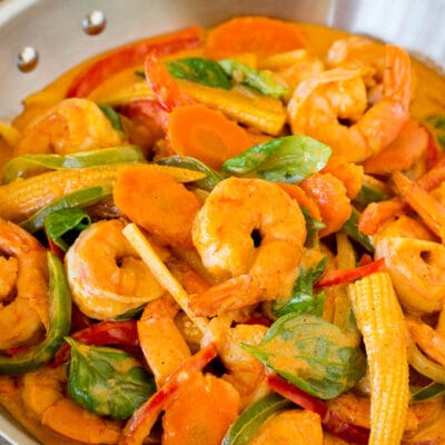 A pan of shrimp curry with assorted vegetables and fresh basil.