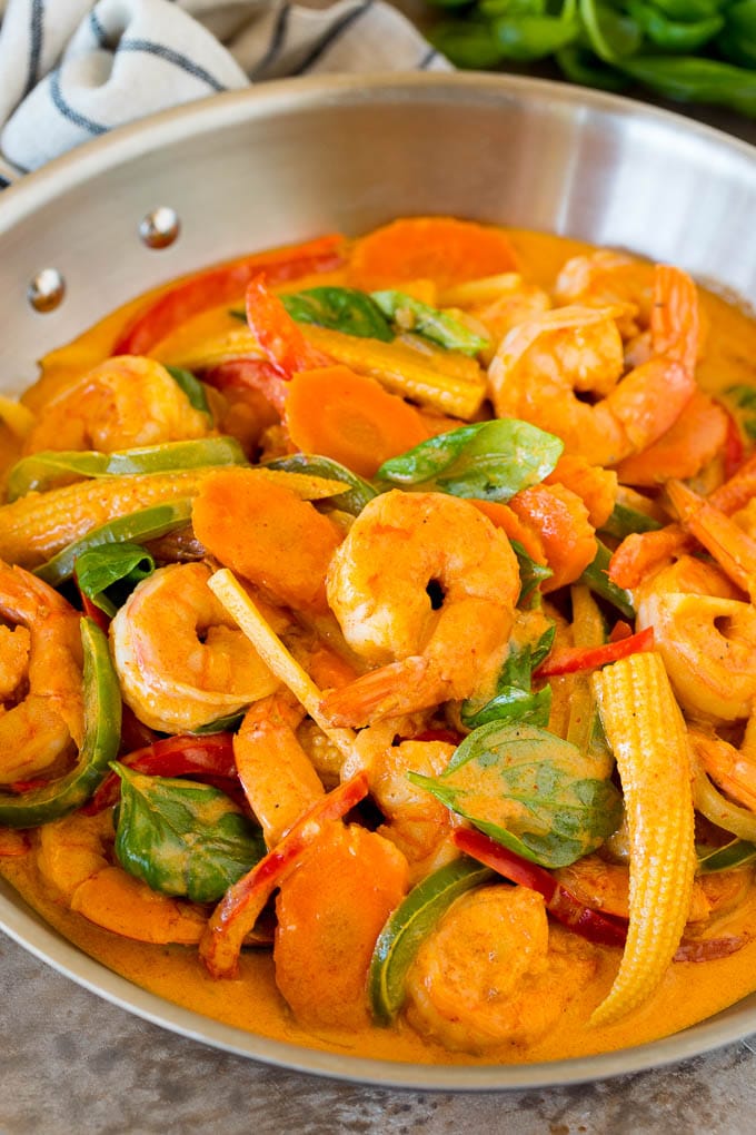 A pan of shrimp curry with assorted vegetables and fresh basil.