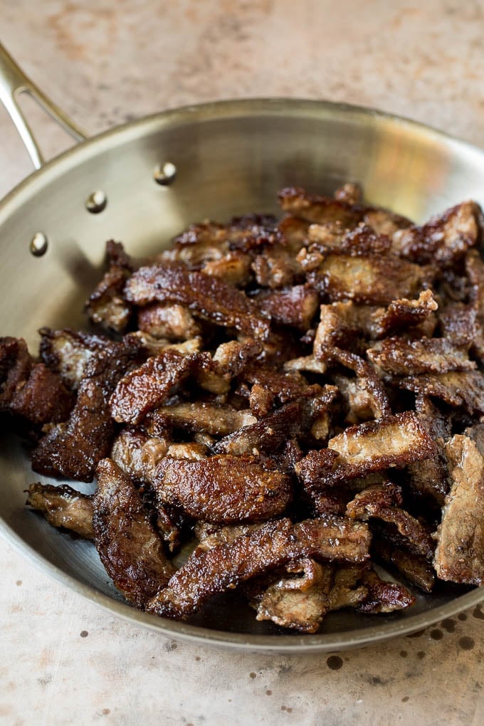 Seared beef slices in a pan.