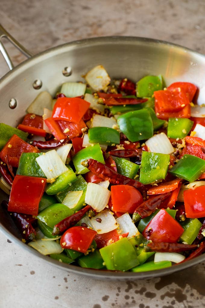 Sauteed vegetables, chilis and peppercorns in a skillet.