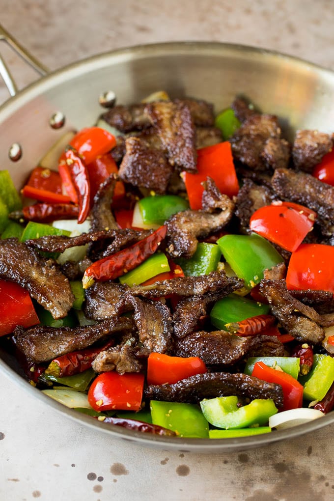 Steak, peppers and onions cooked in a pan.