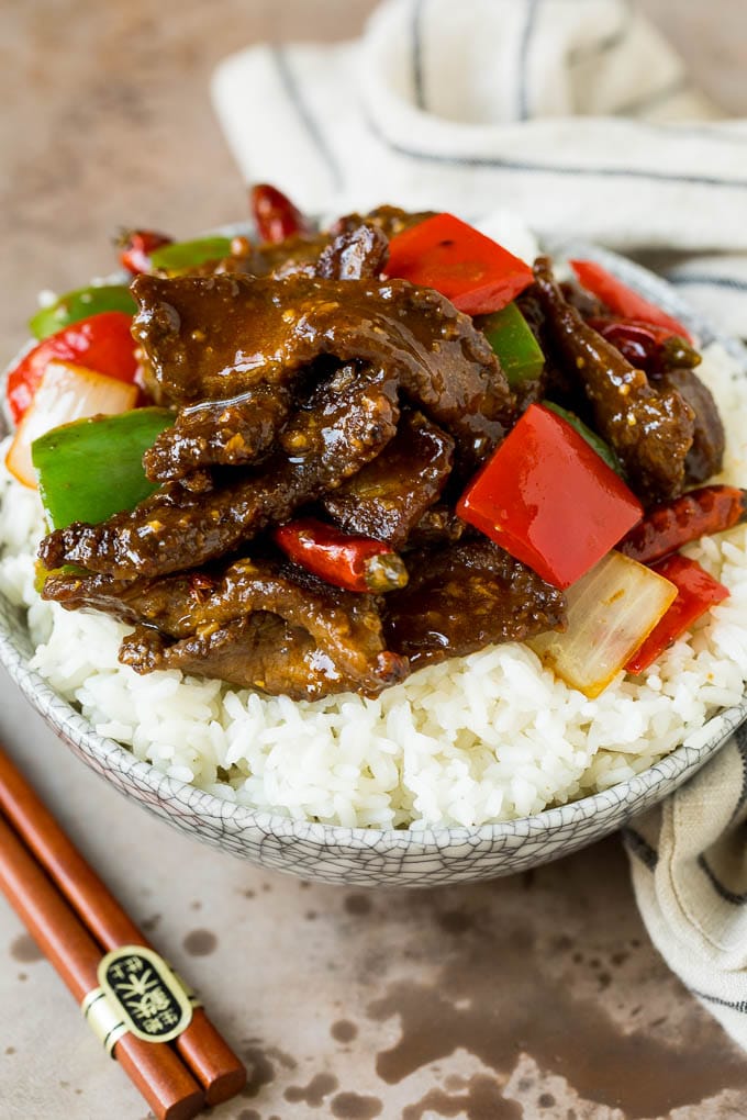 A bowl of Szechuan beef served over steamed rice.