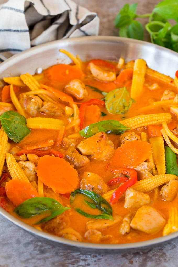 A pan of Thai chicken curry in a creamy red sauce with vegetables.