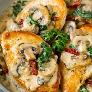A pan of Tuscan chicken topped with creamy mushroom and spinach sauce.