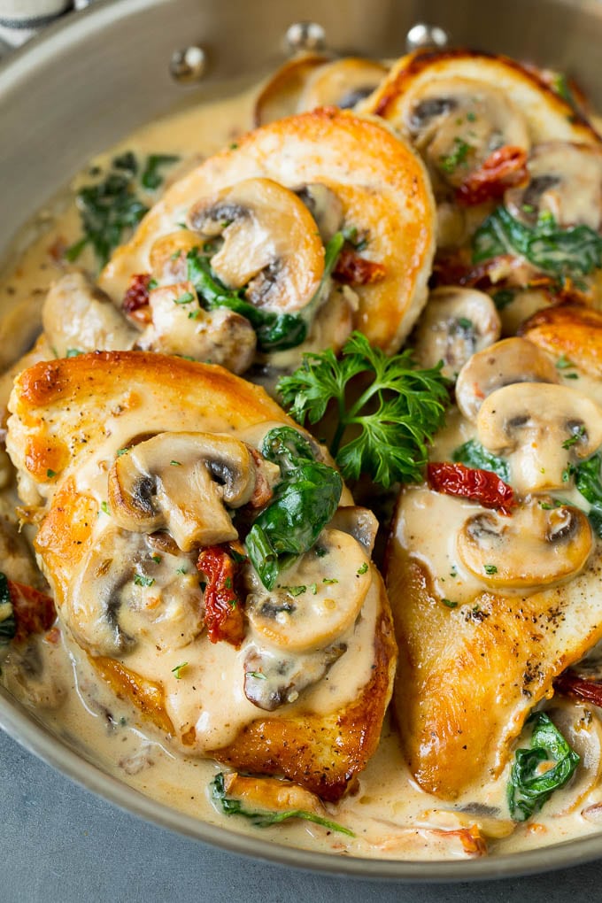 A pan of Tuscan chicken topped with creamy mushroom and spinach sauce.