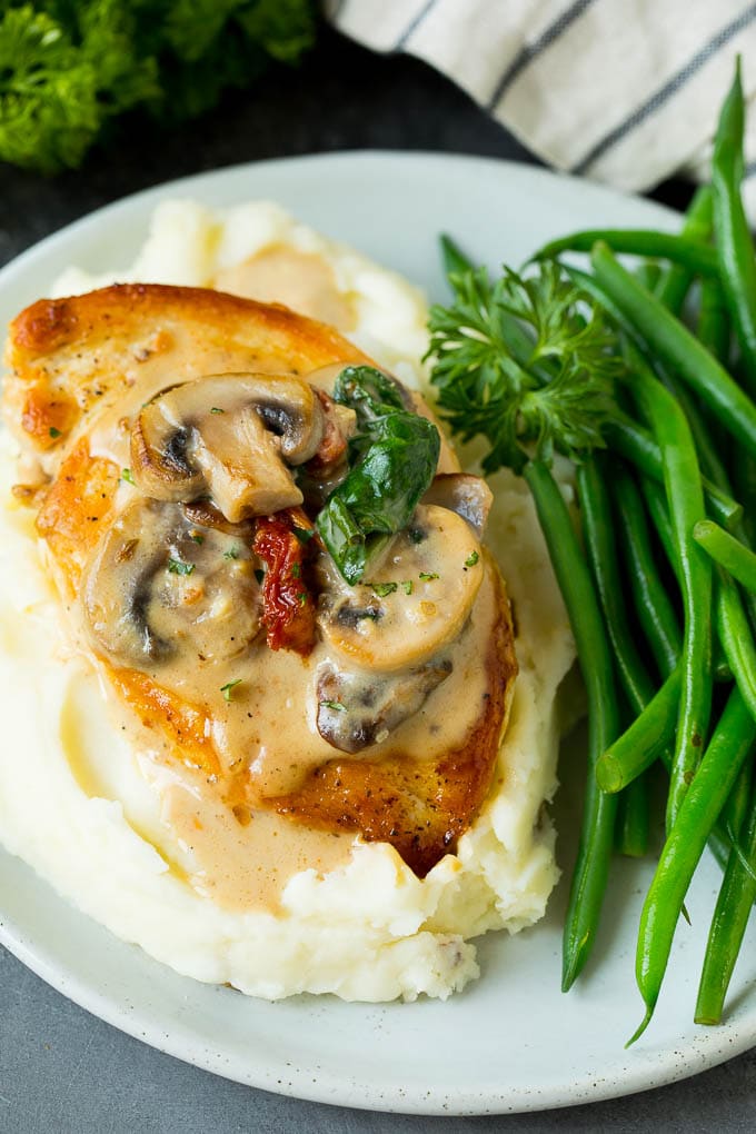 Tuscan chicken served with mashed potatoes and green beans.
