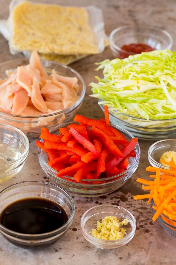 Bowls of shredded vegetables, sliced chicken and seasonings.