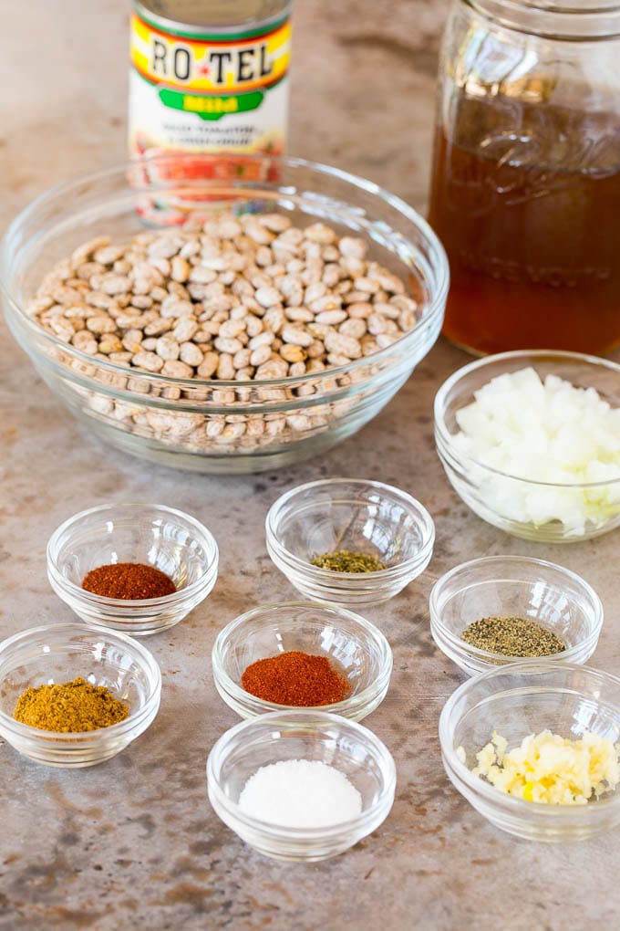 Bowls of ingredients including dry beans, spices and a jar of beef broth.