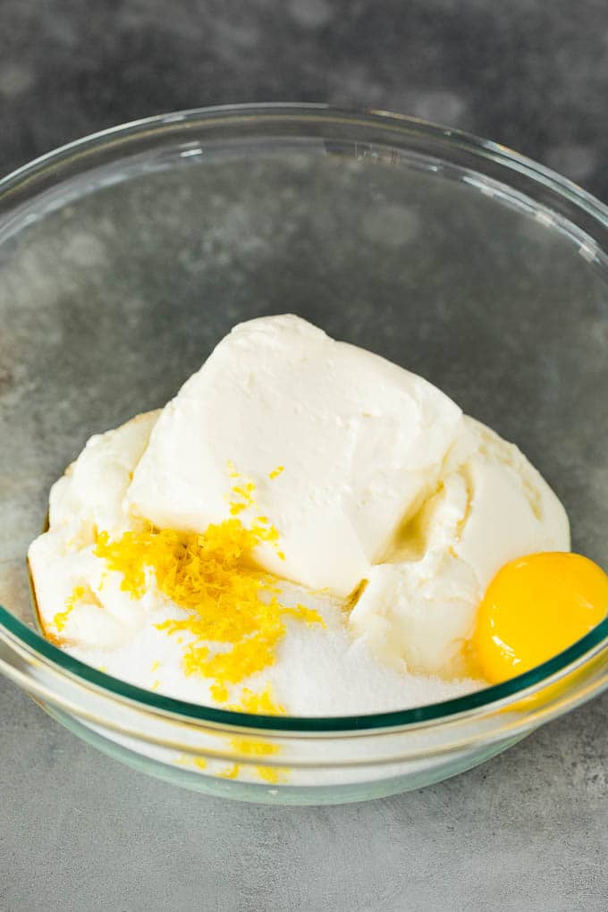 Cheeses, lemon zest, sugar and egg yolk in a bowl.