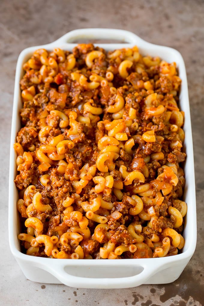 Beef and sauce tossed with macaroni in a baking dish.