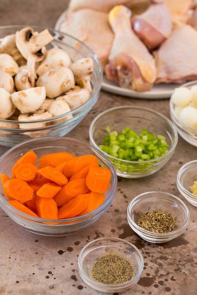 Bowls of vegetables and spices, and a plate of raw chicken.