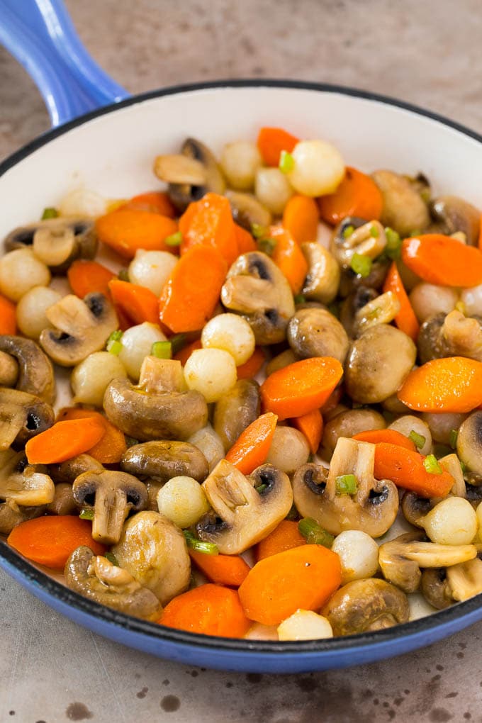 Mushrooms, carrots and pearl onions in a pan.
