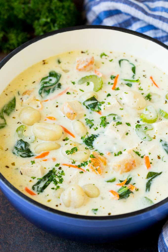 A pot of chicken gnocchi soup with spinach and carrots.