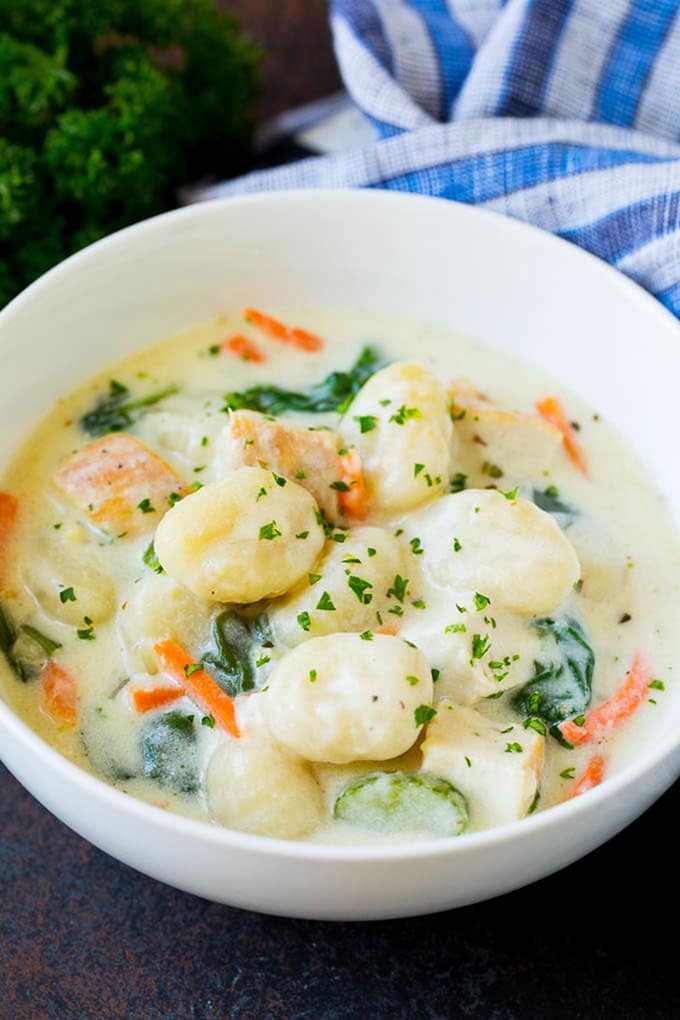 A bowl of creamy gnocchi soup topped with chopped parsley.