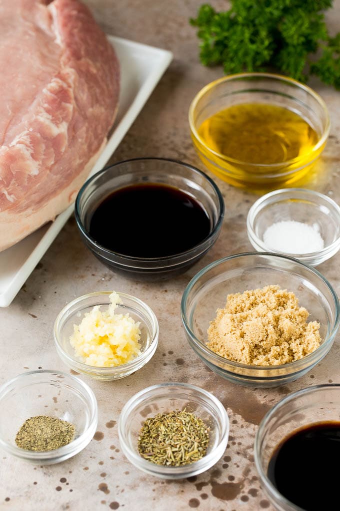 Bowls of herbs, spices and seasonings next to a piece of pork.