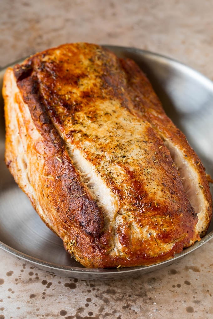 A seared pork loin in a pan.