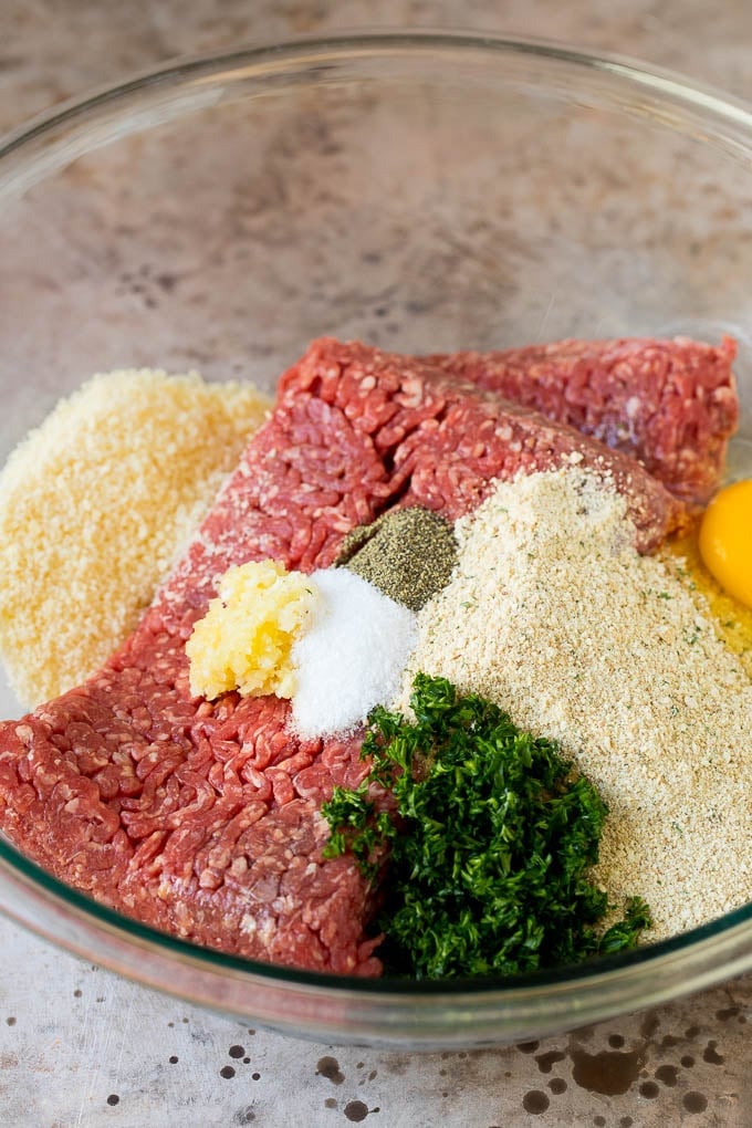 Ground beef, parsley, breadcrumbs and spices in a bowl.