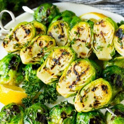 Grilled brussels sprouts on skewers served with lemon and parsley.