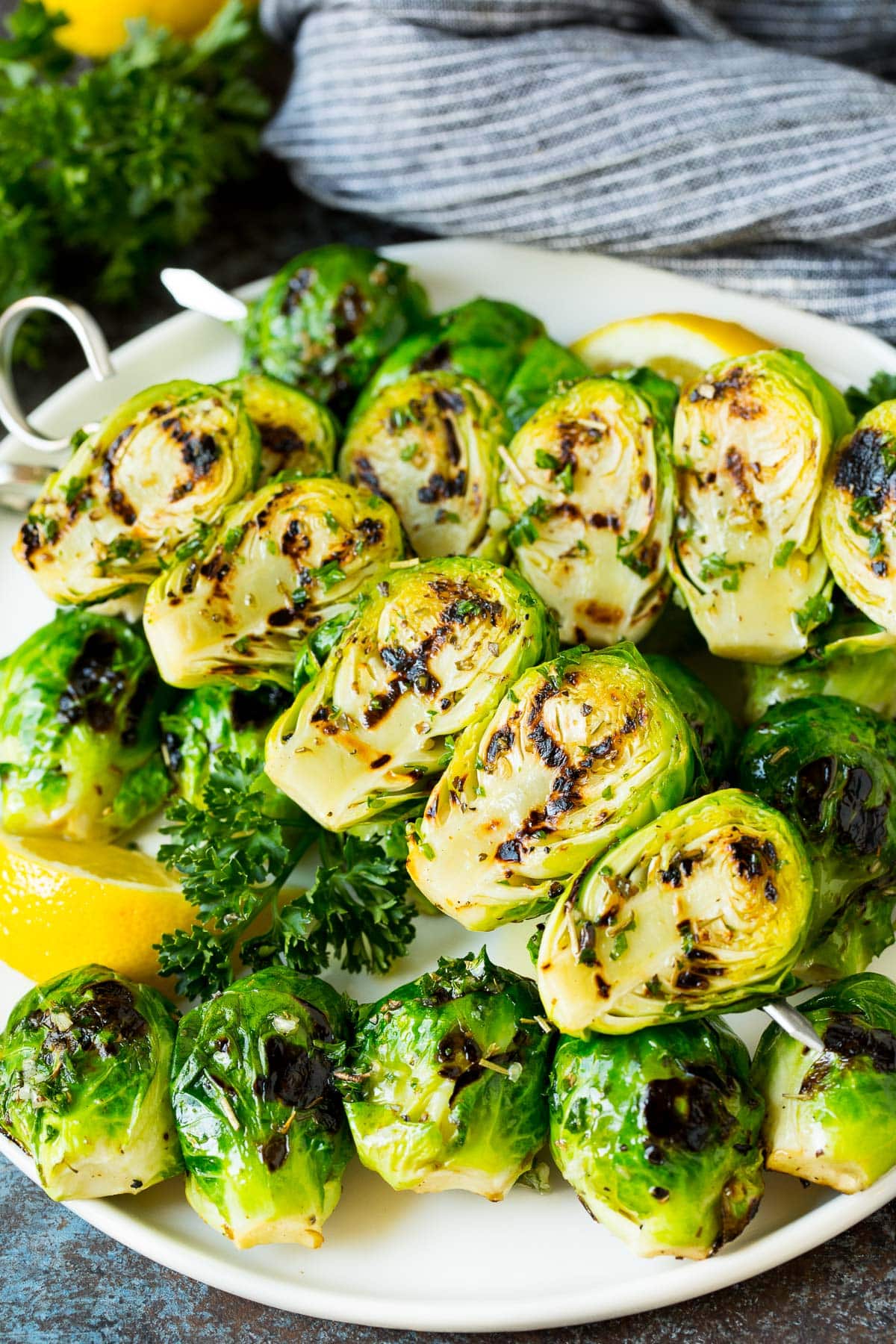 Grilled brussels sprouts on skewers served with lemon and parsley.