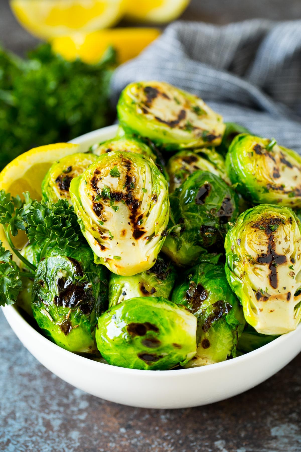 A bowl of grilled brussels sprouts topped with parsley.