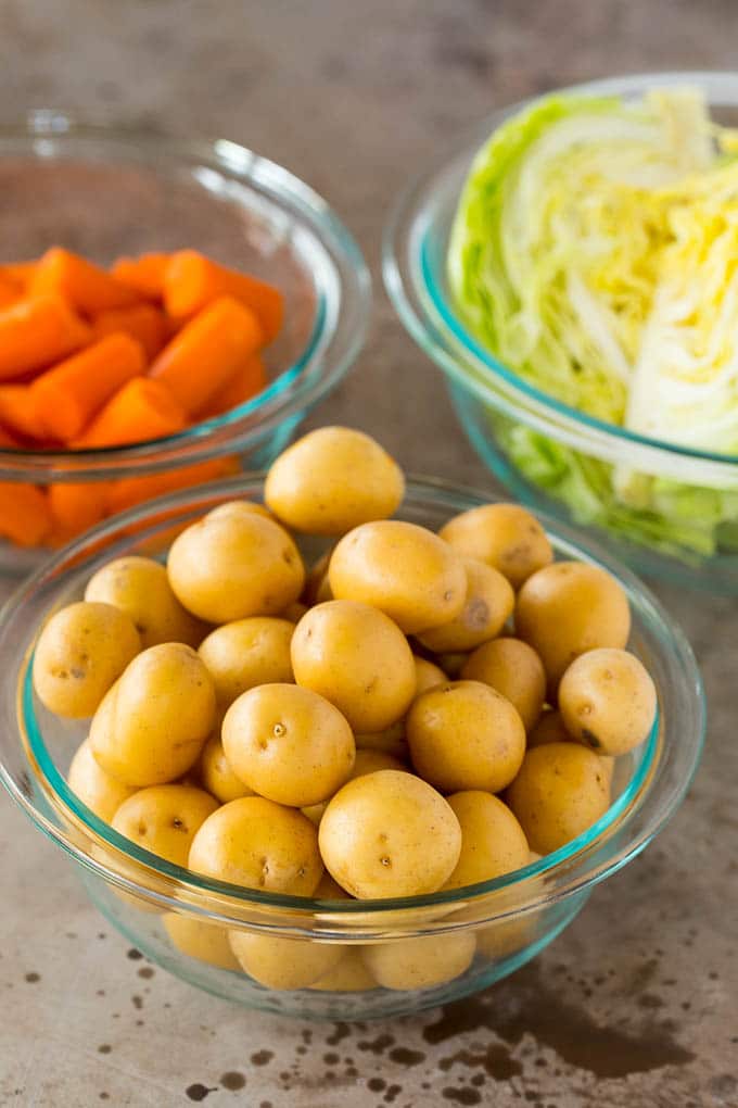 This Instant Pot corned beef is pressure cooked until tender, then served with potatoes, cabbage and carrots in a garlic butter sauce. An easy one pot meal that's great for St. Patrick's Day or any other day of the year! Bowls of potatoes, cabbage and carrots.