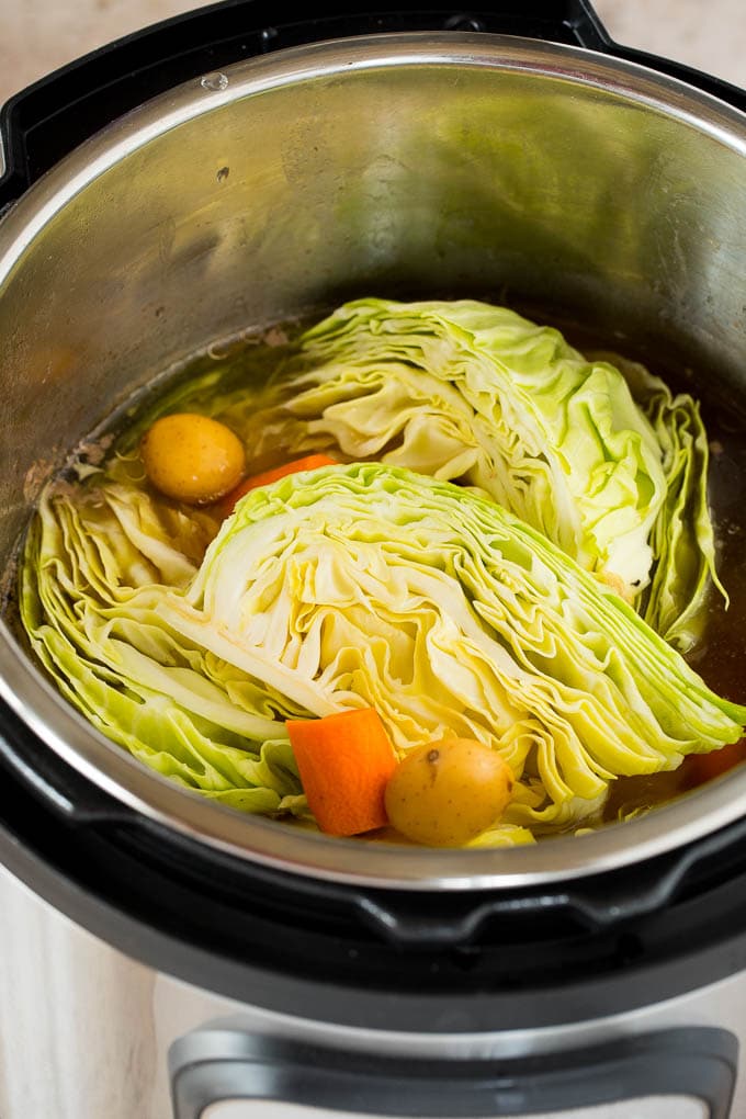 This Instant Pot corned beef is pressure cooked until tender, then served with potatoes, cabbage and carrots in a garlic butter sauce. An easy one pot meal that's great for St. Patrick's Day or any other day of the year! Cabbage wedges, potatoes and sliced carrots in an Instant Pot.