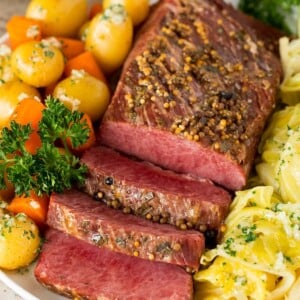 Instant Pot corned beef sliced and served with cabbage, carrots and potatoes.