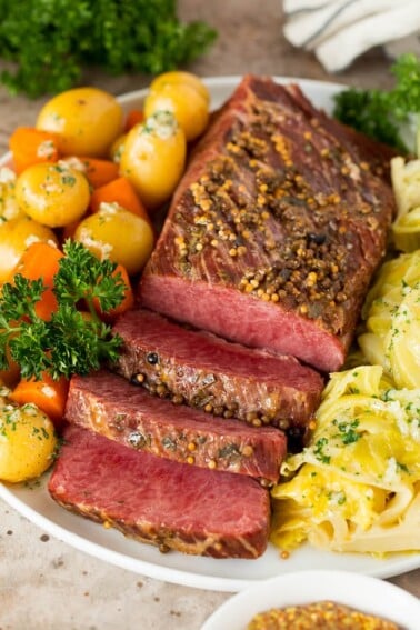 Instant Pot corned beef sliced and served with cabbage, carrots and potatoes.