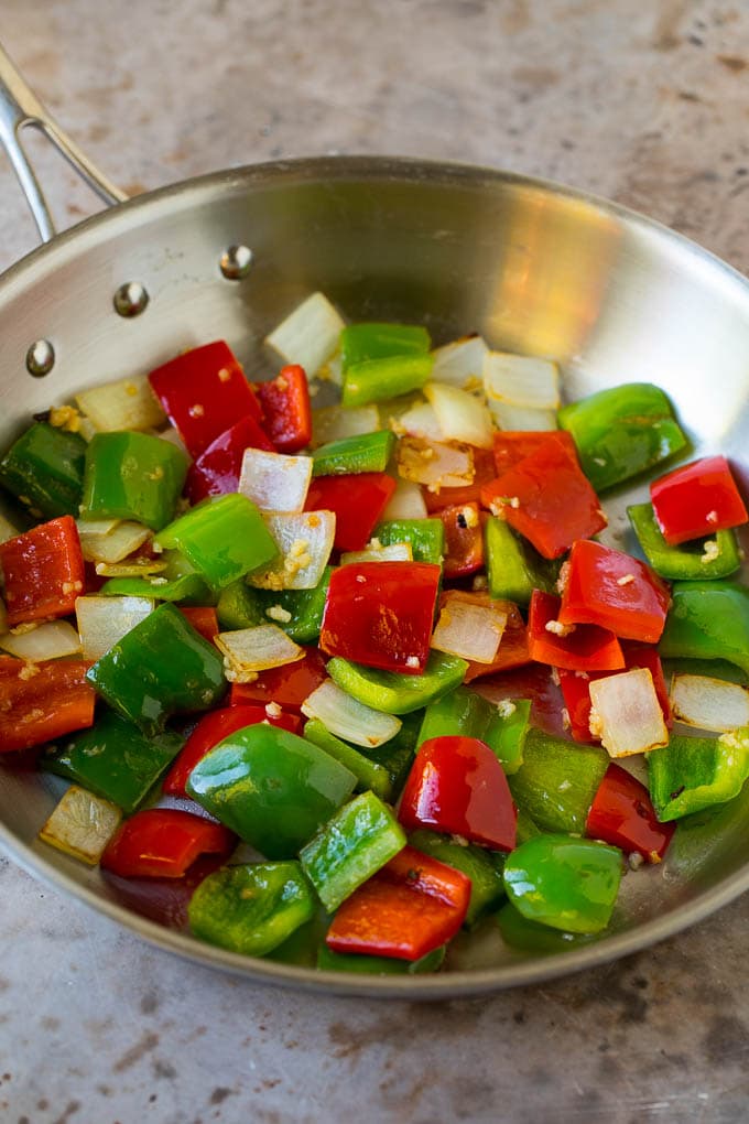 Bell peppers, onions and garlic cooked in a skillet.