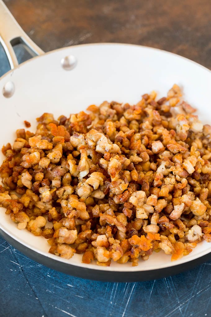 Browned diced chicken in a skillet.