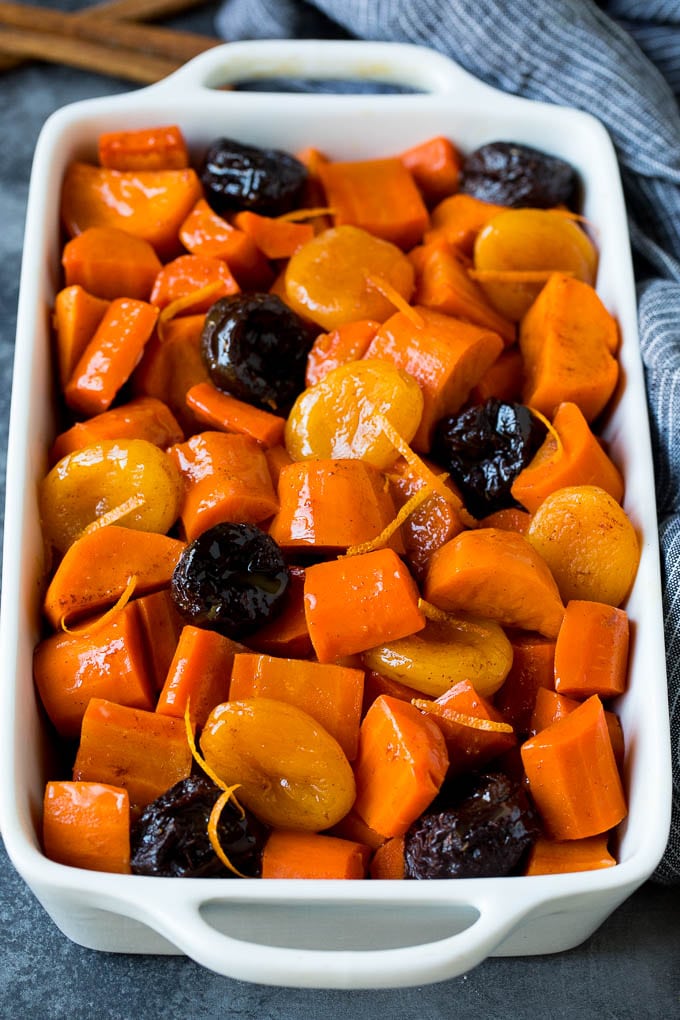 A baking dish of tzimmes garnished with orange zest.
