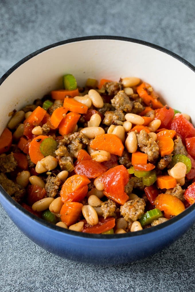 A mixture of beans, tomatoes, vegetables and sausage in a pot.