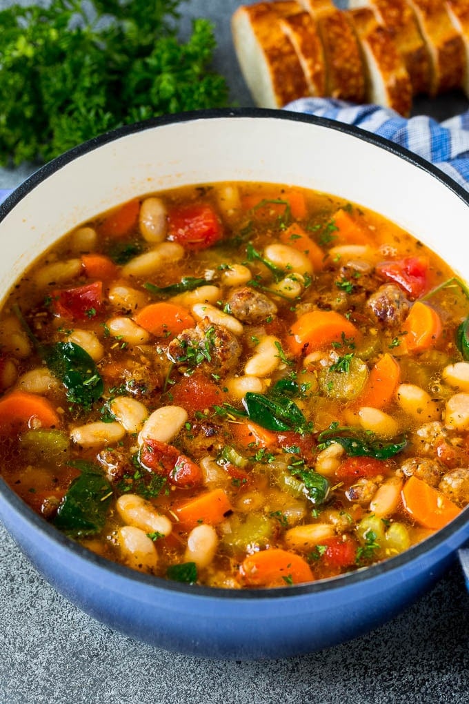 A pot of Tuscan white bean soup with sausage and vegetables.